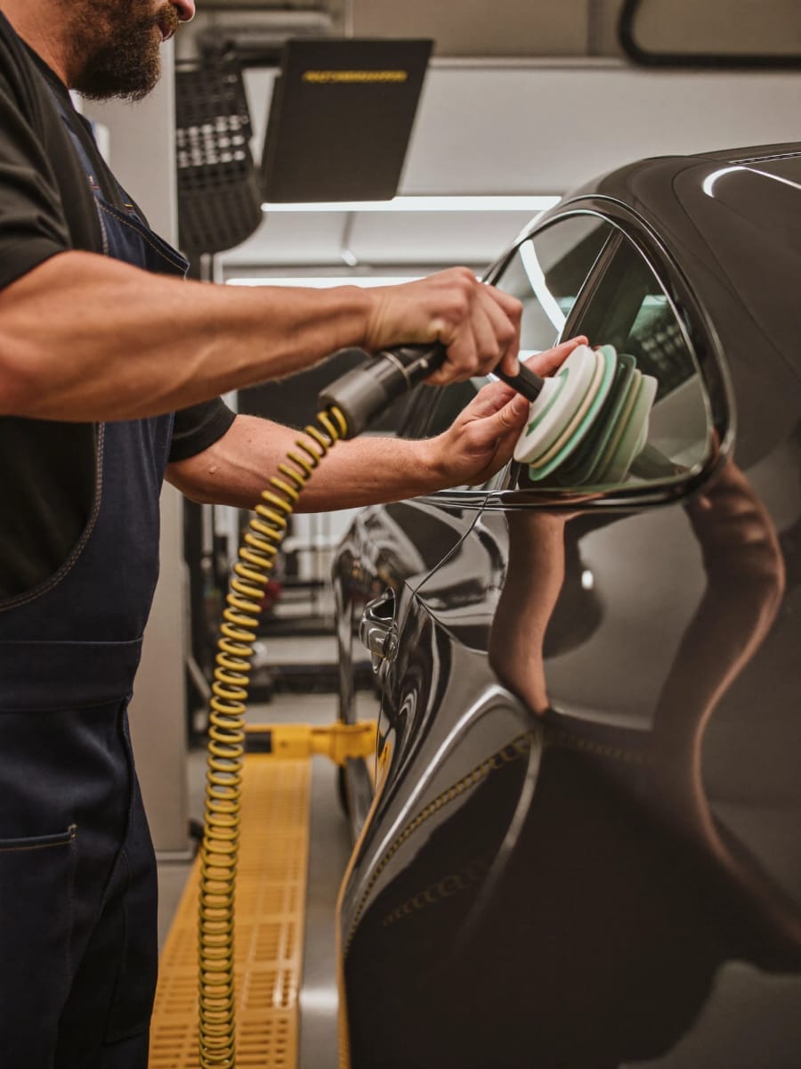 A detailer polishing a car in a workshop